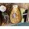 A handmade sunflower vase that is part of an open shelving display. The vase is made from a dried gourd. It sits next to vintage books.